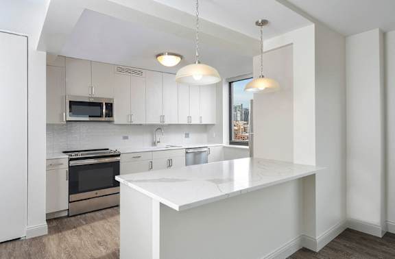 A kitchen with a white island and pendant lights.