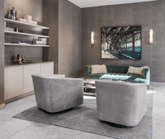 A modern living room with a green couch and grey ottoman.