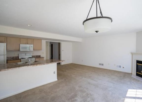 View from dining area of great room towards living area with fireplace and kitchen with breakfast bar