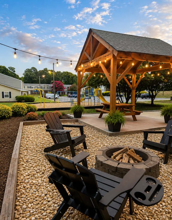 A wooden pavilion with a fire pit and chairs in the foreground.