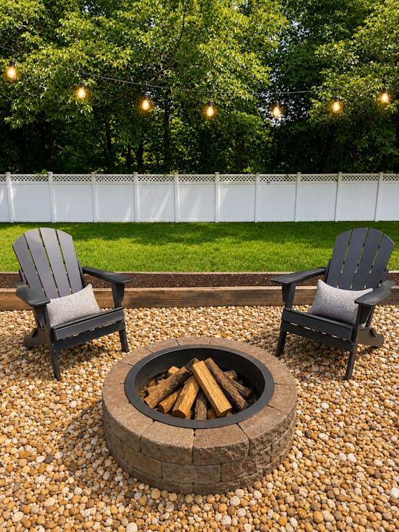 Two chairs are placed around a fire pit on a gravel patio.