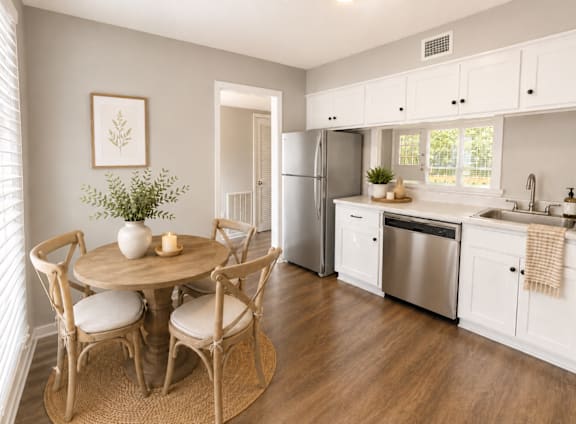 A kitchen with a table and chairs in the foreground and a refrigerator in the background.