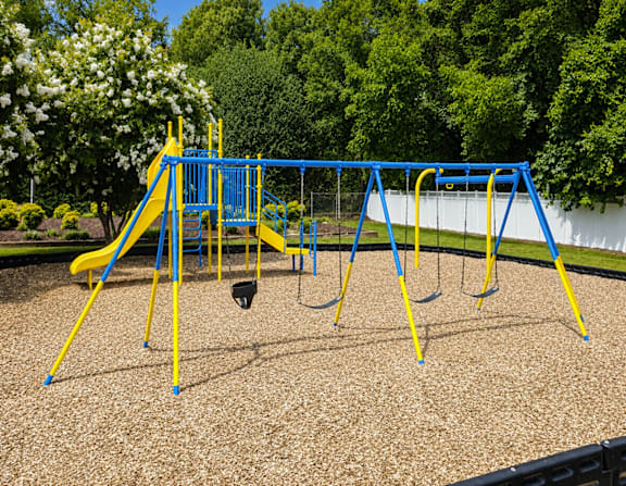 A playground with a blue and yellow swing set.