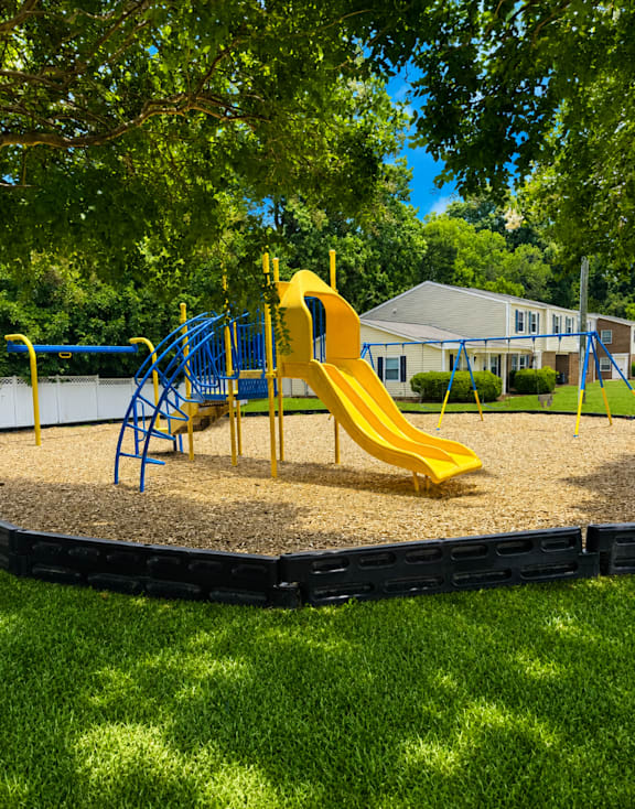 A playground with a yellow slide and blue play structure.