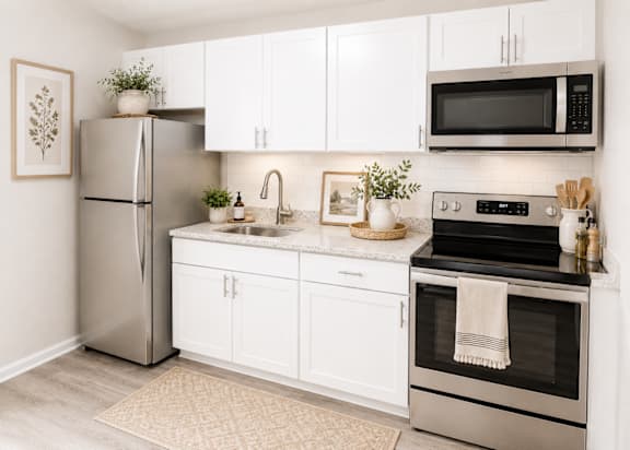 A modern kitchen with white cabinets and stainless steel appliances.