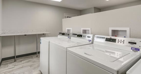 a row of white washing machines in a laundromat