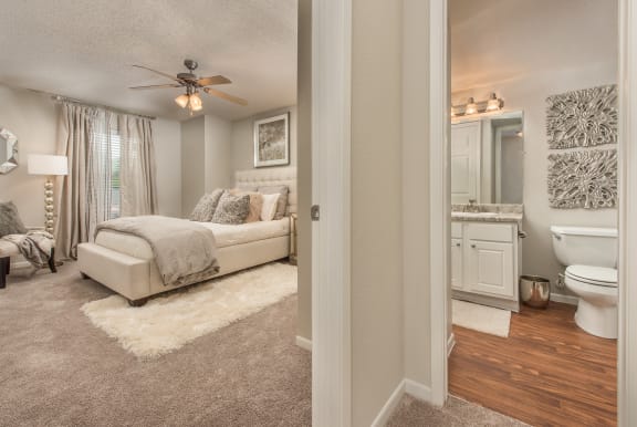 a bedroom and bathroom with a ceiling fan