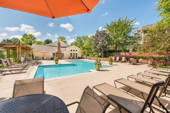a pool with chairs and tables and a building in the background