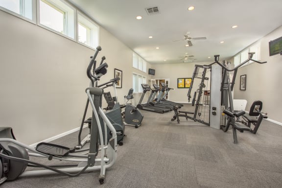 a gym with weights and cardio equipment in a building with windows