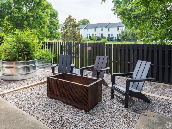 a patio with two chairs and a firepit in front of a fence at Capital Flats & Magnolia Square Apartments, Raleigh, NC, 27601