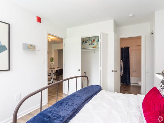 a bedroom with a bed and a view of the living room and dining room at Capital Flats &amp; Magnolia Square Apartments, Raleigh, NC, 27601