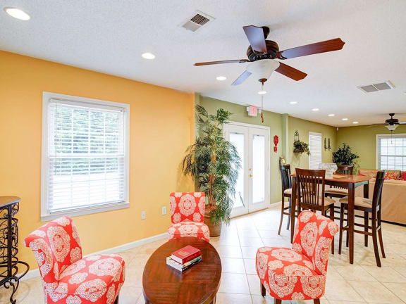 a living room with a table and chairs and a ceiling fan