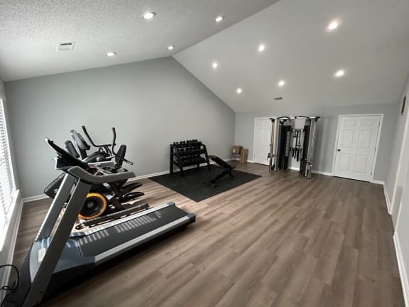 a home gym with a treadmill and weights on a wooden floor
