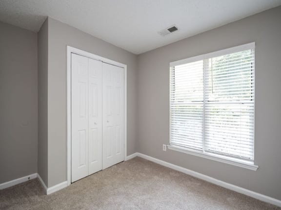 an empty bedroom with a large window and a white door