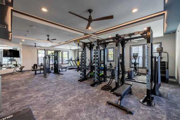 A spacious gym with a variety of equipment including a squat rack, bench, and weights.