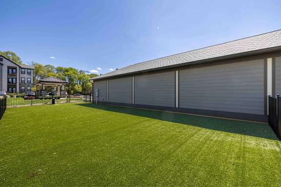 A large grassy area in front of a building with a closed grey garage door.