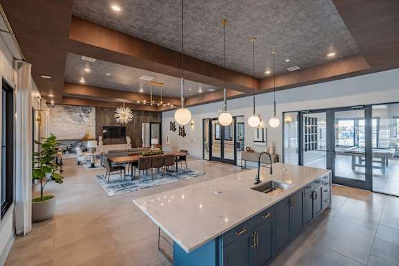 A modern kitchen with a large island and pendant lights.