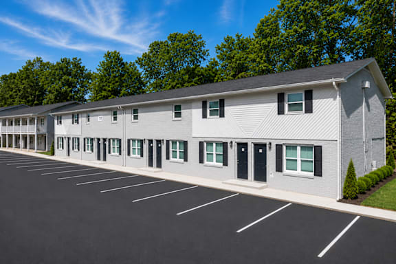 A long building with a parking lot in front.
