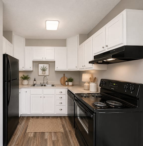 A black stove in a kitchen with white cabinets.