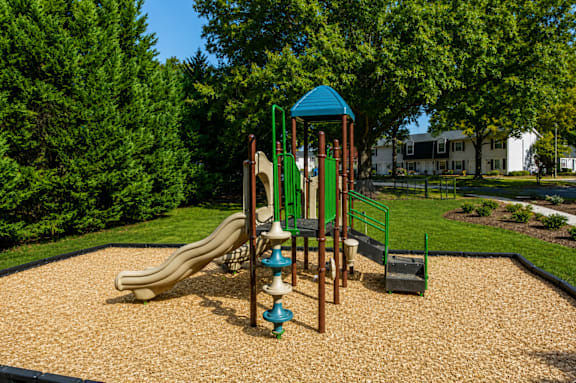 A playground with a slide, swings, and a playhouse.
