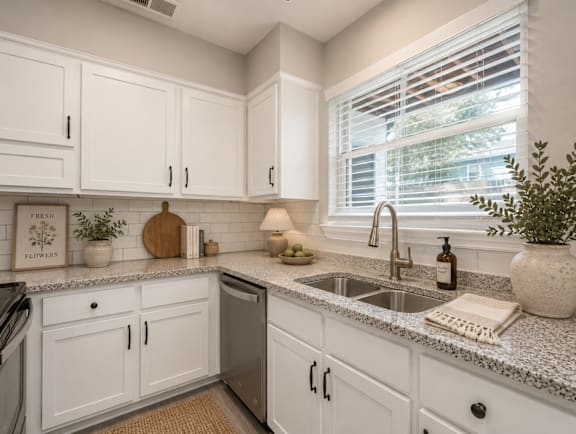 A kitchen with white cabinets and granite countertops.