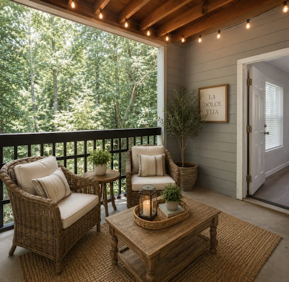 A cozy balcony with a wicker chair, a sofa, a coffee table, and a potted plant.