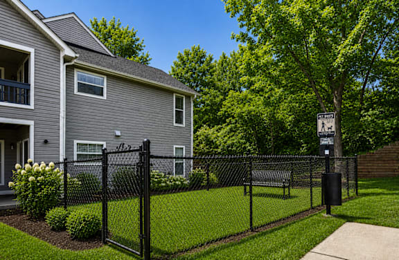 A grey house with a black fence and a sign on the tree.