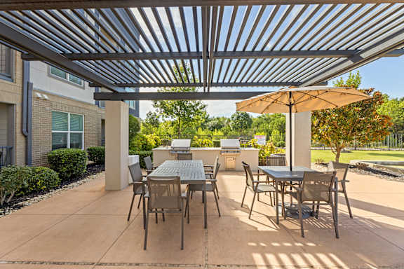 A patio with a table and chairs under a metal roof.
