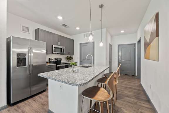 A kitchen with a granite countertop and stainless steel appliances.