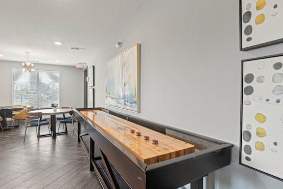 A shiny wooden pool table in a room with a painting on the wall.
