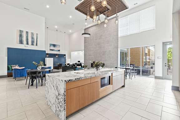 A modern kitchen with a marble island and pendant lights.