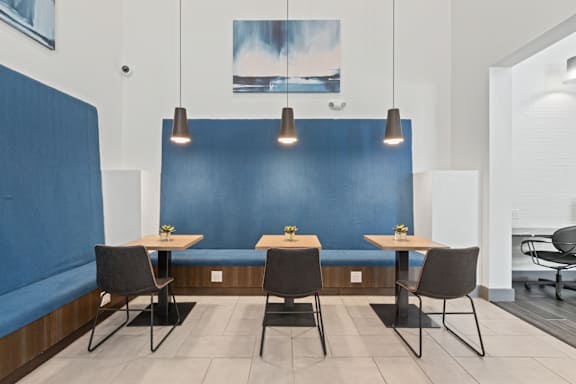 A blue booth with a table and chairs in front of it.