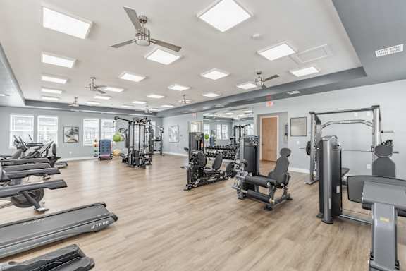 A gym with a variety of equipment including treadmills, weights, and a squat rack.