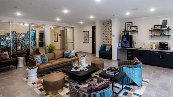 A living room with a brown couch, a coffee table, and a blue chair at Hudson at Renaissance Apartments, Wilmington, NC 28405
