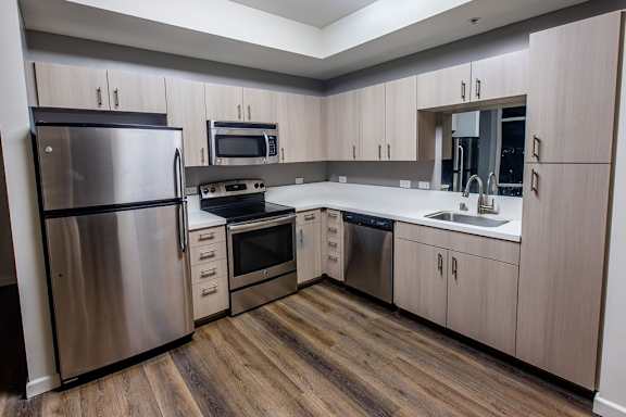 A kitchen with a stainless steel refrigerator, microwave, oven, and sink.
