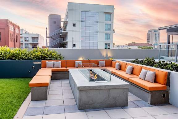 A modern outdoor seating area with a fire pit and cushioned benches.