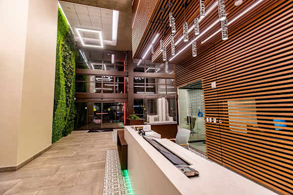 A modern office lobby with a green wall and a reception desk.
