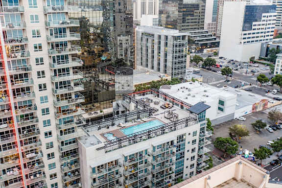 A view of a city from a high angle with buildings, cars and a pool visible.
