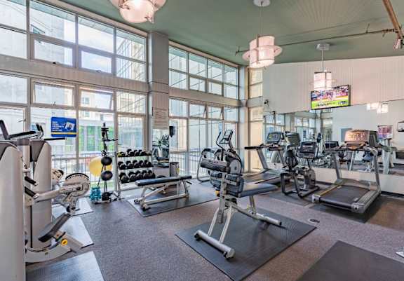 A gym with a variety of equipment including treadmills, weights, and exercise machines.