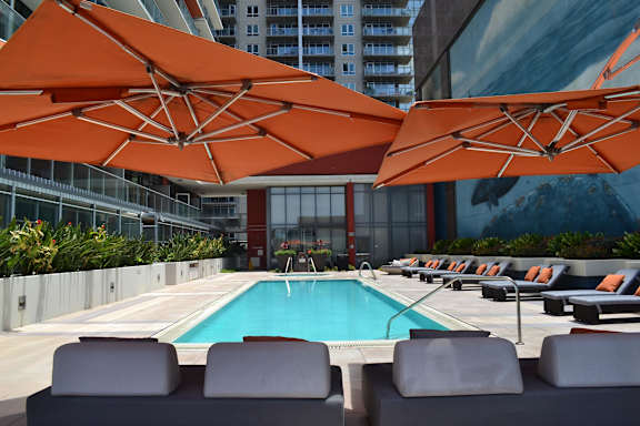 A pool surrounded by orange umbrellas and lounge chairs.