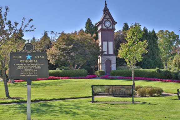 a sign for blue star memorial with a clock tower in the middle of a park