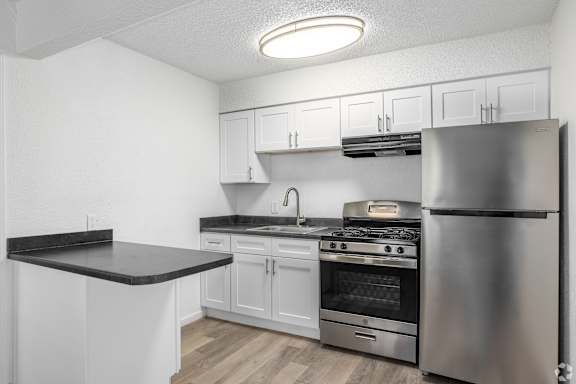 A kitchen with white cabinets and a stainless steel refrigerator.