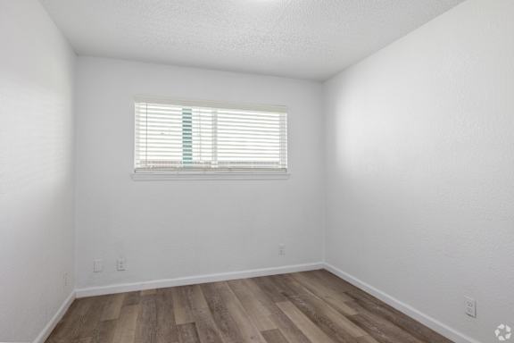 A room with a window and wooden flooring.