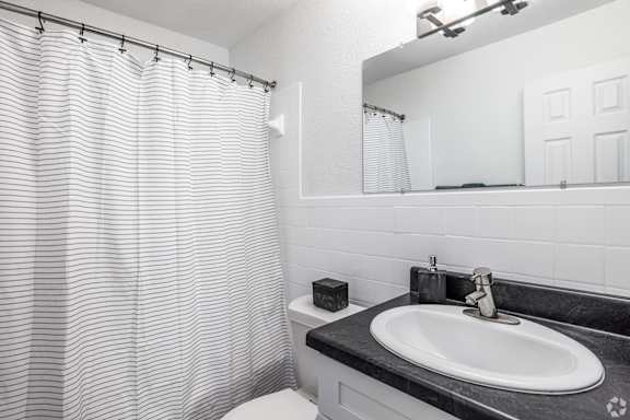 A bathroom with a sink, mirror, and shower curtain.