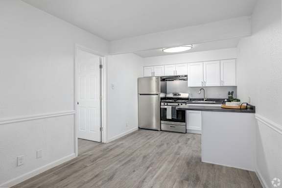 A kitchen with white cabinets and a stainless steel refrigerator.