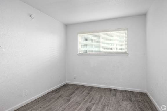 A room with a window and wooden flooring.