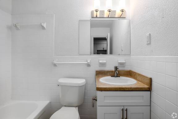 A white bathroom with a toilet, sink, and bathtub.