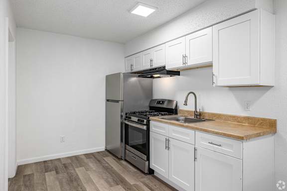 A kitchen with white cabinets and a wooden countertop.