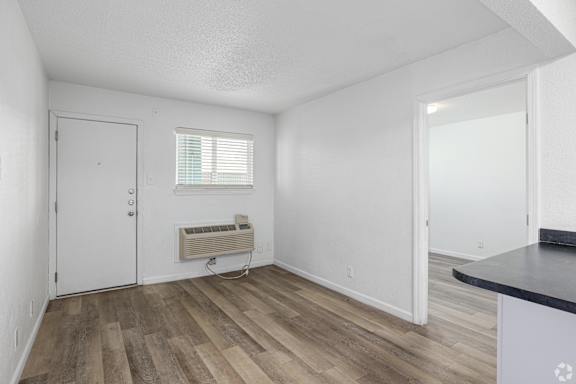 A room with a white door, a window with blinds, and a radiator on the wall.
