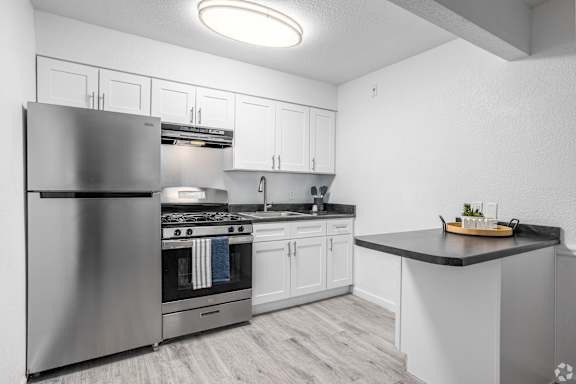 A modern kitchen with a stainless steel refrigerator and a black countertop.